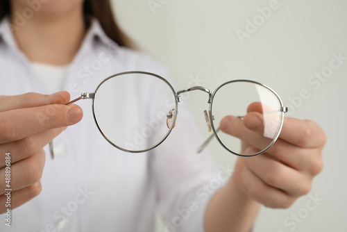 Woman with glasses on light background, closeup