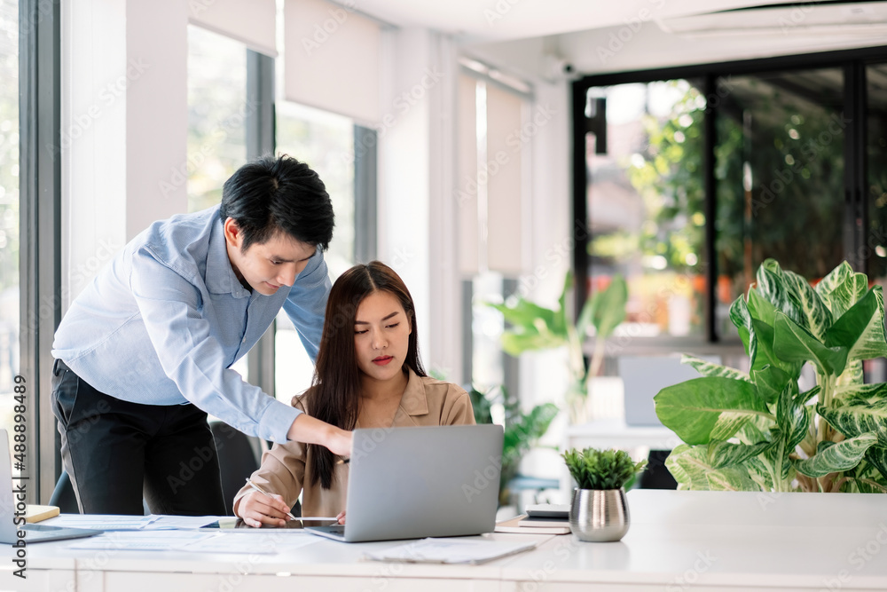 Entrepreneur Asian businessman and woman discussing new business project in laptop computer in modern meeting room. Entrepreneur Asian businessman and woman discussing new business project in laptop computer in modern meeting room.
