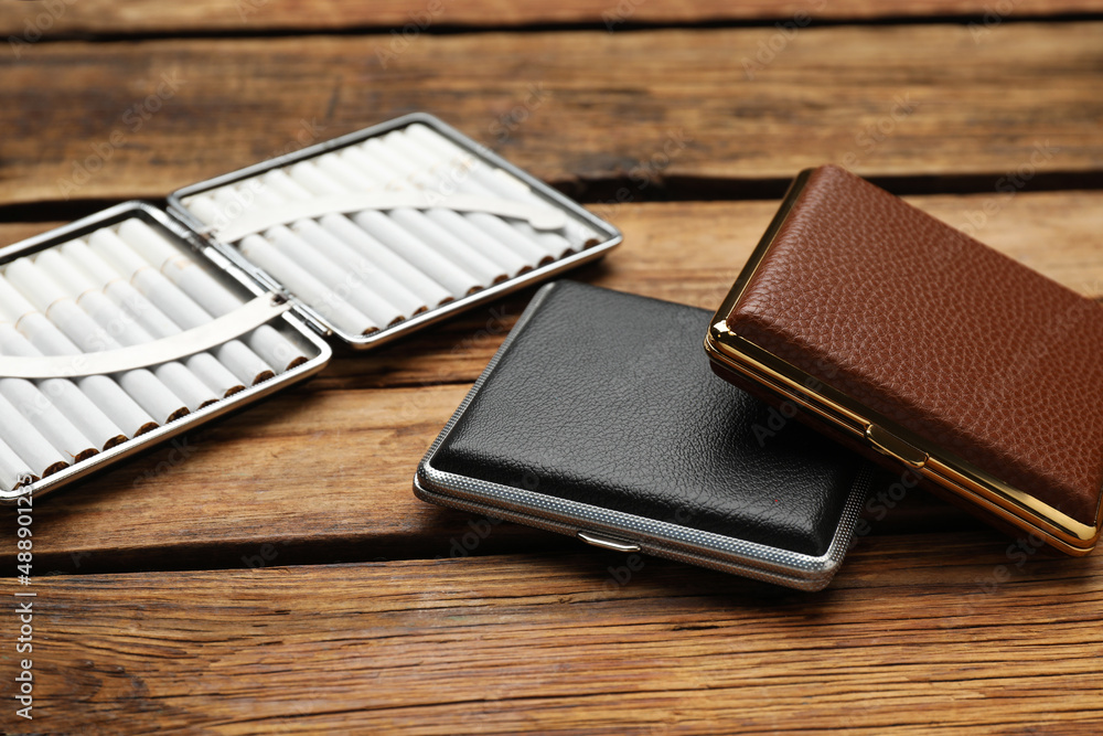 Stylish leather cigarette cases on wooden table Stylish leather cigarette cases on wooden table