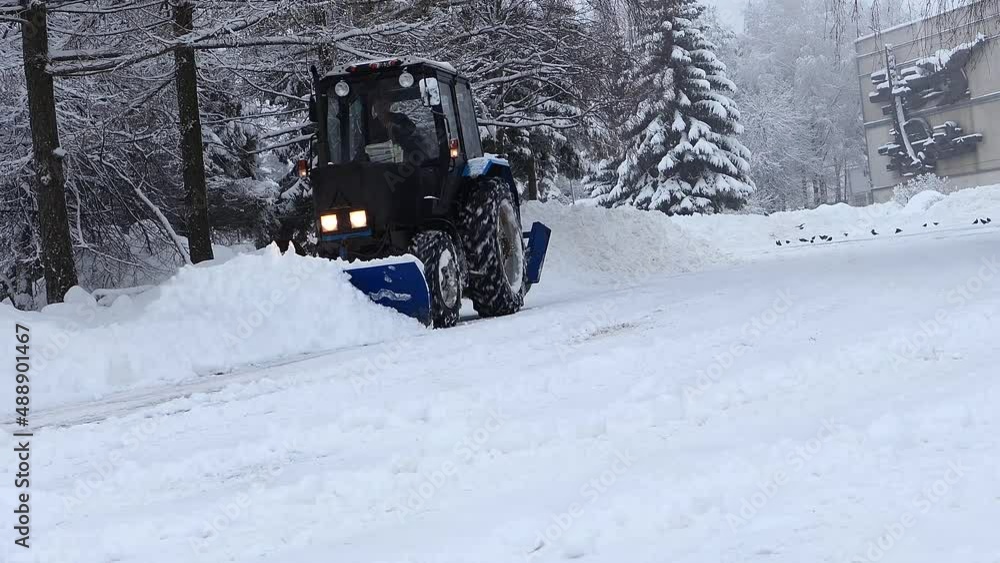 Snowfall in the city. A large tractor, snow removal equipment removes snow from the streets of the city. Winter cyclone