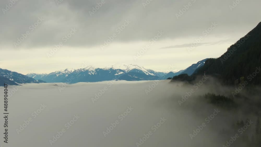 Aerial View of Canadian Mountain Landscape covered in fog over Harrison Lake. Dramatic Colorful Winter Sunset Sky Art Render. British Columbia, Canada. Nature Background Panorama Aerial View of Canadian Mountain Landscape covered in fog over Harrison Lake. Dramatic Colorful Winter Sunset Sky Art Render. British Columbia, Canada. Nature Background Panorama