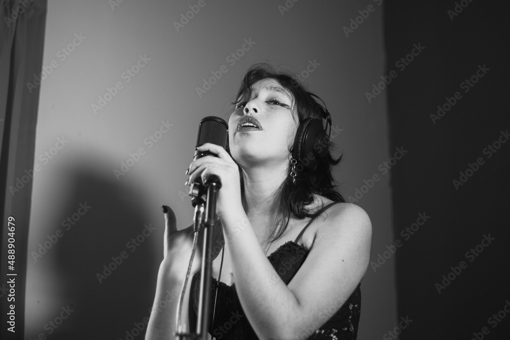 Mujer joven cantando contenta en un estudio musical a blanco y negro Mujer joven cantando contenta en un estudio musical a blanco y negro