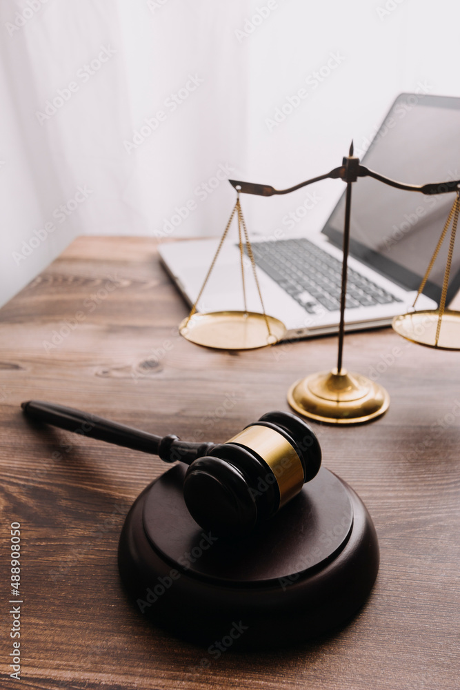 Partial view of lawyers in suits working together on project at workplace with gavel and laptop in office Partial view of lawyers in suits working together on project at workplace with gavel and laptop in office