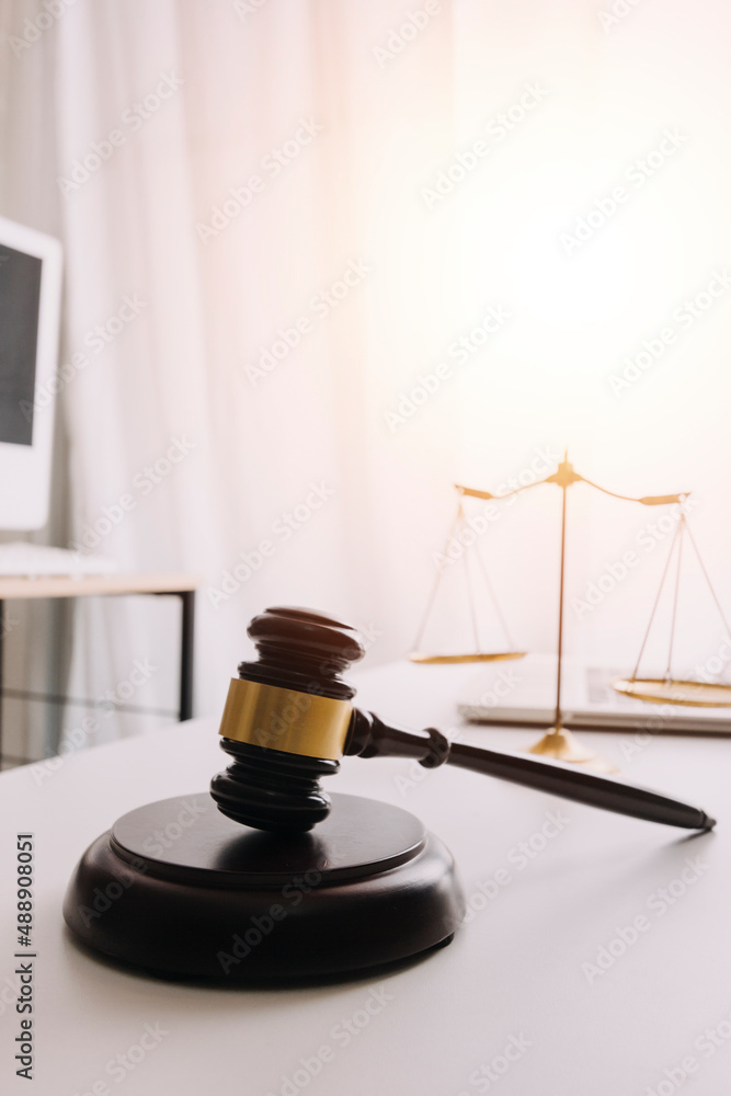 Partial view of lawyers in suits working together on project at workplace with gavel and laptop in office Partial view of lawyers in suits working together on project at workplace with gavel and laptop in office