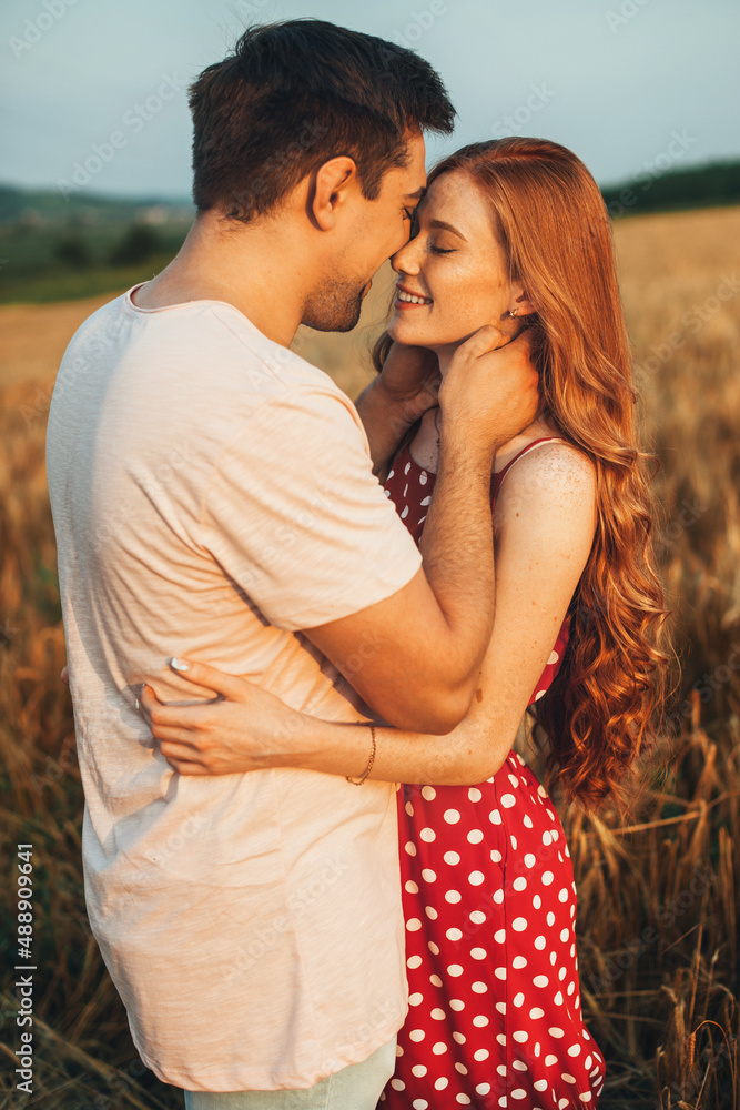Couple standing close to each other in the wheat field away from the city, following a kiss. Nature landscape. People lifestyle concept. Couple standing close to each other in the wheat field away from the city, following a kiss. Nature landscape. People lifestyle concept.