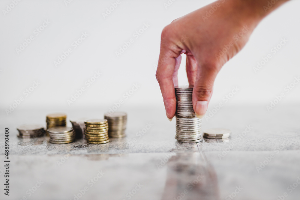 Obraz na plátně hand placing stacks of different coins on white background shot at shallow depth