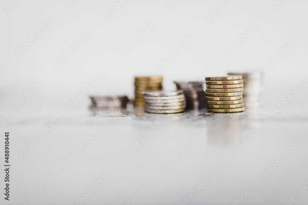 stacks of different coins on white background shot at shallow depth of field with minimalist composition stacks of different coins on white background shot at shallow depth of field with minimalist composition