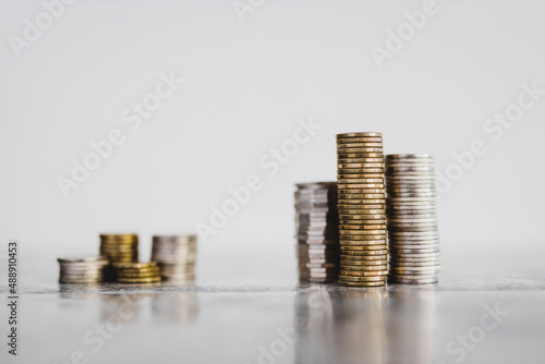 stacks of different coins divided between a small and a big group on white background, good vs bad investements or before and after investing