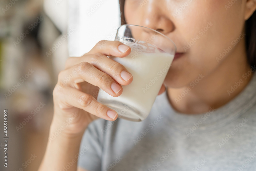 Happy, Asian young woman, girl drinking a glass of white fresh, warm or hot dairy milk for calcium, vitamin wholesome good nutrition in morning at kitchen home. lifestyle, product healthy people. Happy, Asian young woman, girl drinking a glass of white fresh, warm or hot dairy milk for calcium, vitamin wholesome good nutrition in morning at kitchen home. lifestyle, product healthy people.