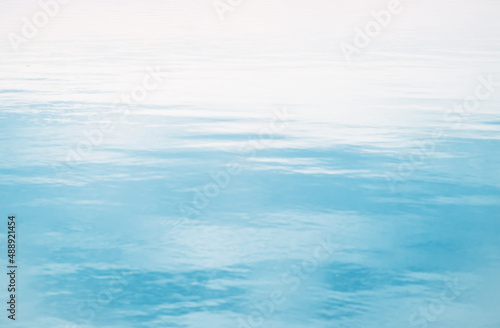 defocused blue relaxing sea or ocean water surface background at dusk with sky reflection. summer travel or vacation overlay with ripples pattern. top view