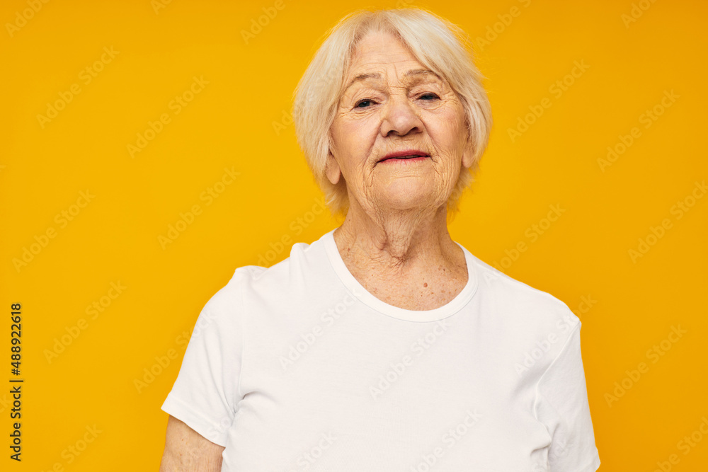 Portrait of an old friendly woman posing face grimace joy yellow background Portrait of an old friendly woman posing face grimace joy yellow background
