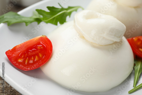 Delicious burrata cheese with arugula and tomato on wooden table, closeup #488922823