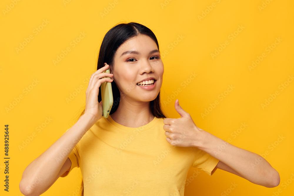 woman with Asian appearance communicates on the phone emotions yellow background unaltered