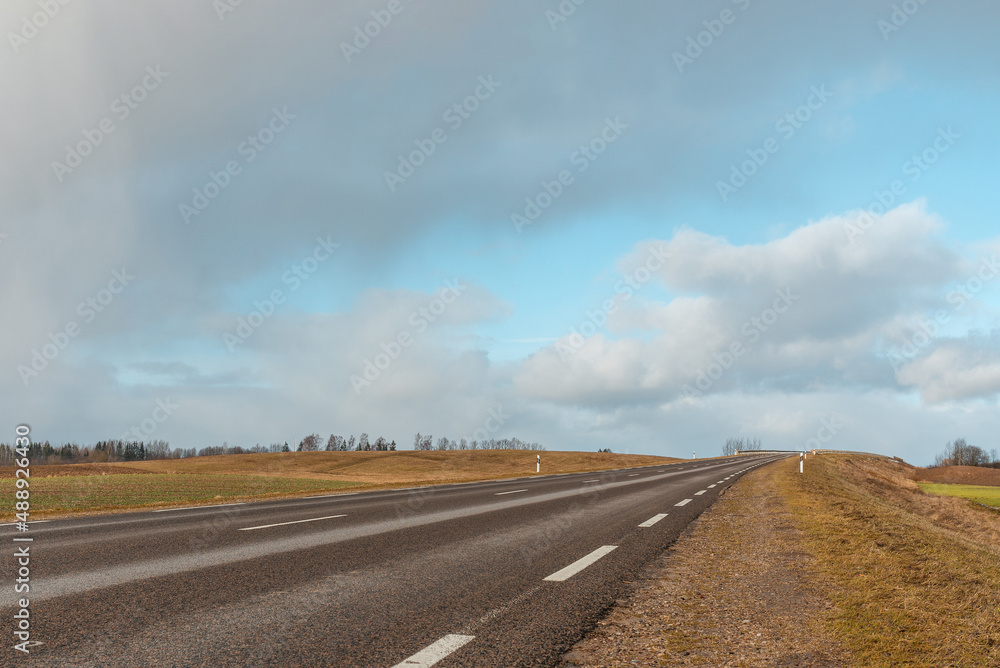 Empty road asphalt landscape among green spring meadows , blue sky,white clouds.