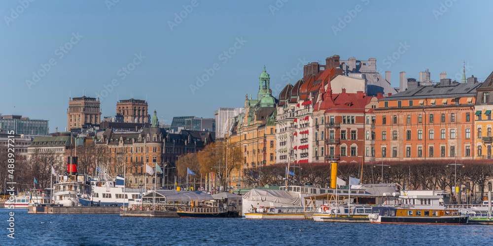 Panorama view over a creek of the bay Ladugårdsviken with commuting boats surrounded by office and hotel buildings a sunny winter day in Stockholm