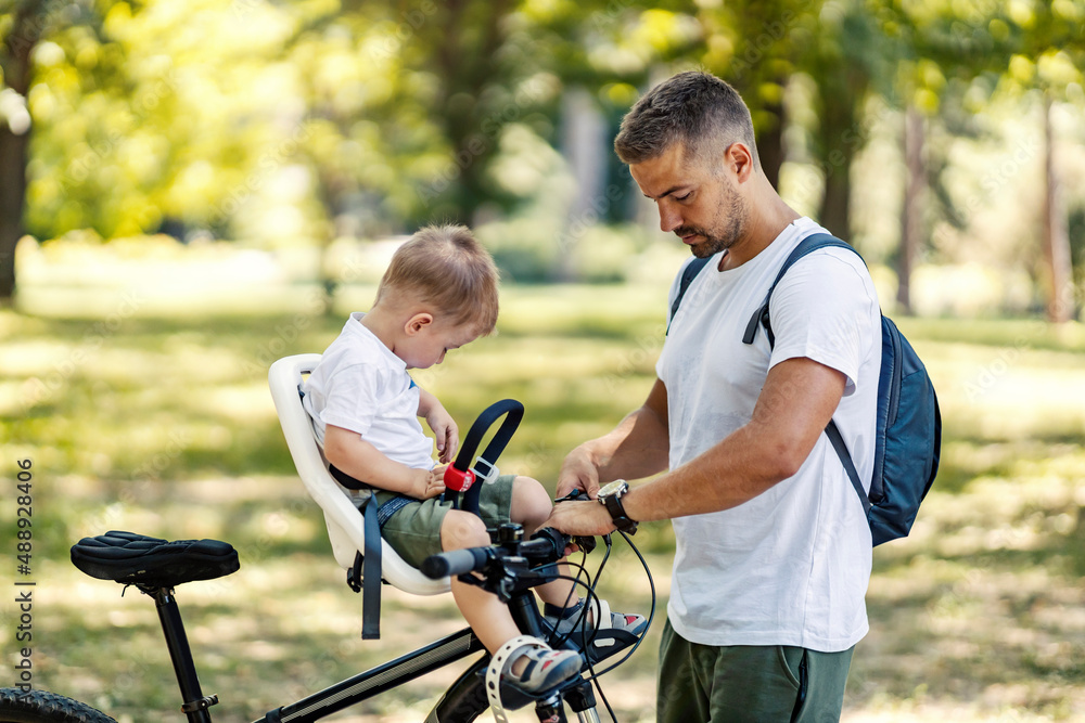Obraz premium Father preparing his son for bicycle ride in nature.