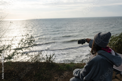 Young woman takes a photo on a smartphone of the seascape