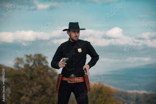 Sheriff or marshal. American western, wild west with cowboy. Serious guy with gun revolver weapon outdoor.