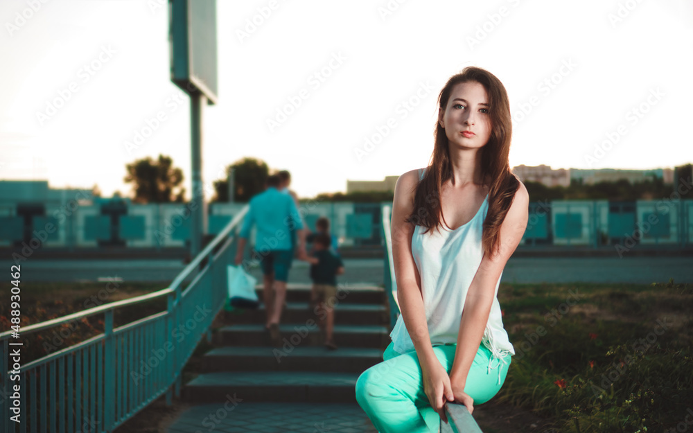 Beautiful young woman with long hair sits on handrail, outdoor. Spring mood. City life concept. Beautiful young woman with long hair sits on handrail, outdoor. Spring mood. City life concept.