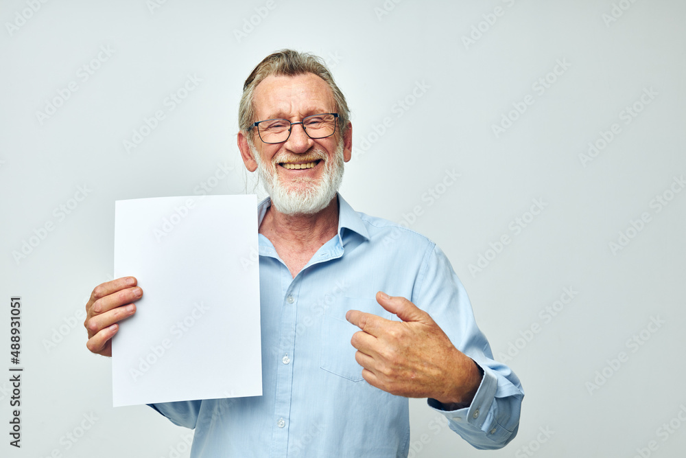 Photo of retired old man holding a sheet of paper copy-space posing isolated background Photo of retired old man holding a sheet of paper copy-space posing isolated background