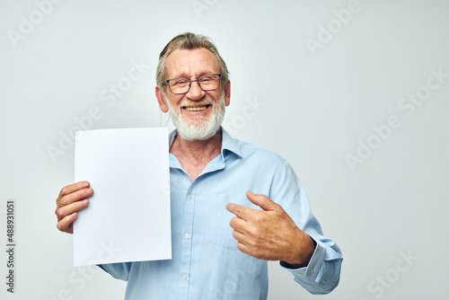 Photo of retired old man holding a sheet of paper copy-space posing isolated background