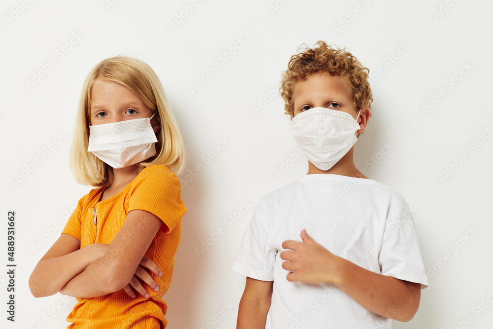 Boy and girl fun medical mask stand side by side close-up light background