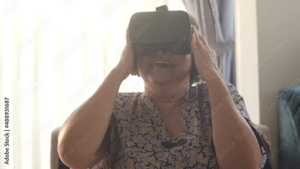 Happy senior woman using VR Headset virtual reality simulator in a living room,Slow motion Happy senior woman using VR Headset virtual reality simulator in a living room,Slow motion