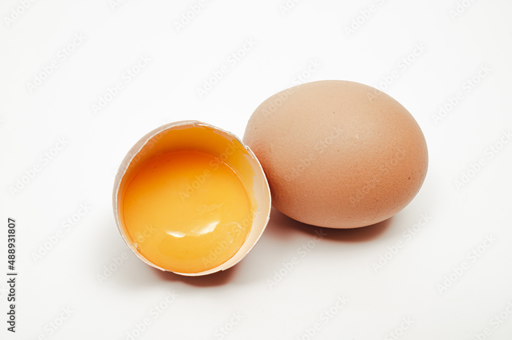 Broken egg with yolk visible on white background Broken egg with yolk visible on white background