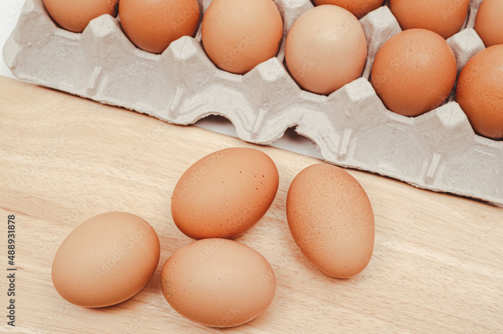 The eggs on the paper tray and wooden chopping board. The eggs on the paper tray and wooden chopping board.