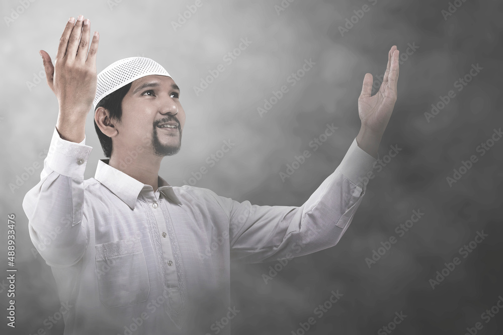 Asian Muslim man standing while raised hands and praying Asian Muslim man standing while raised hands and praying