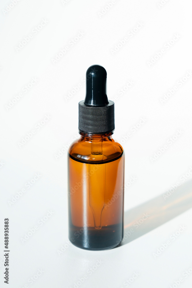 Bottle with dropper pipette with serum or essential oil. White background with daylight. Skincare products , natural cosmetic. Beauty concept for face and body care Bottle with dropper pipette with serum or essential oil. White background with daylight. Skincare products , natural cosmetic. Beauty concept for face and body care