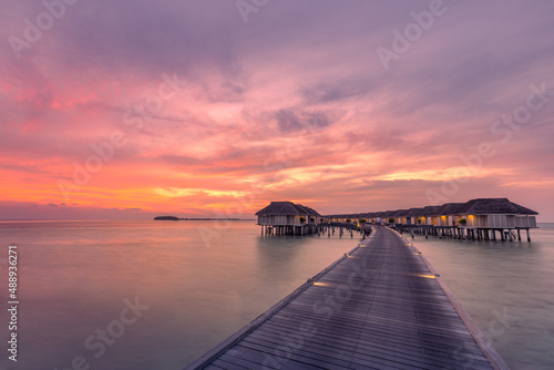 Fantastic sunset landscape in the Maldives. Amazing clouds and colorful sky water villas  bungalows over tranquil ocean lagoon. Tropical island beach  sea  traveling destination. Luxury vacation