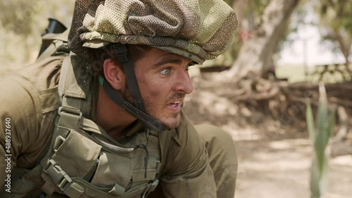 Male soldier filling his water bottle in a blurry water pool trying to survive while looking around. Close-up shot photo