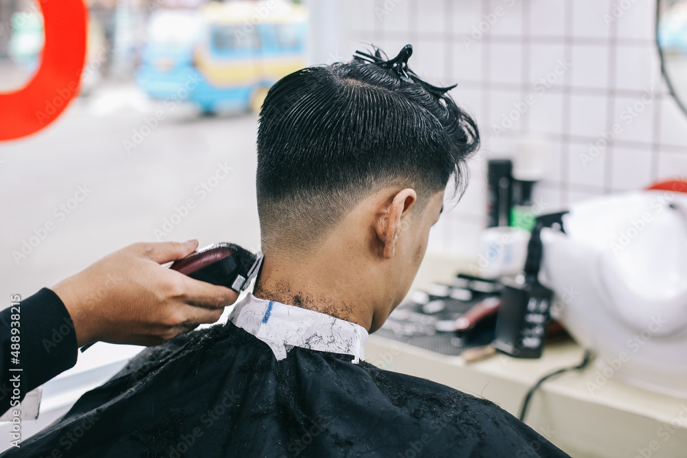 Back view of hairdresser shaving consumer's hair with clipper. Back view of hairdresser shaving consumer's hair with clipper.