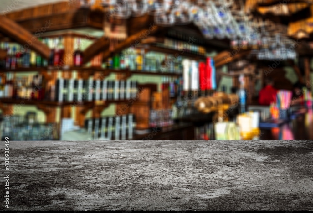Grey table top and beautiful bokeh shelves with alcohol bottles on the background. Bar concept.