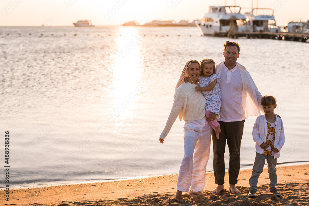 Family having fun, holding hands and running on a sandy beach Family having fun, holding hands and running on a sandy beach