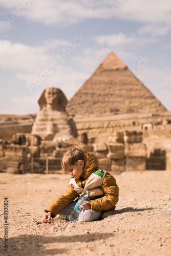 boy plaing on background of Great Sphinx and Chephren's pyramid in Giza, Egypt