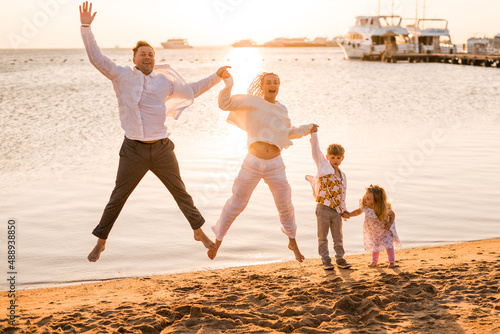 happy family holding hands and jumping on beach