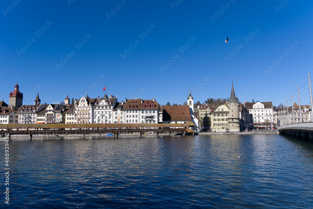Fototapeta premium Medieval old town of Luzern with famous covered wooden Chapel Bridge (German: Kapellbrücke) and stone water tower on a sunny winter day. Photo taken February 9th, 2022, Lucerne, Switzerland.
