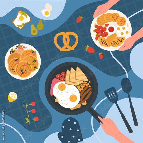 Breakfast, morning food menu set from restaurant and cafe on kitchen table. Hand holding frying pan with fried eggs, beans, sausages, cereal toast pancakes cookies with strawberry jam on plates