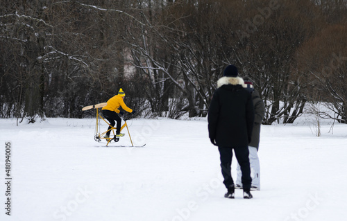 A cyclist with a propeller rides in the snow in winter.Winter bike. Bike with skis. Wooden propeller on a bicycle. photo