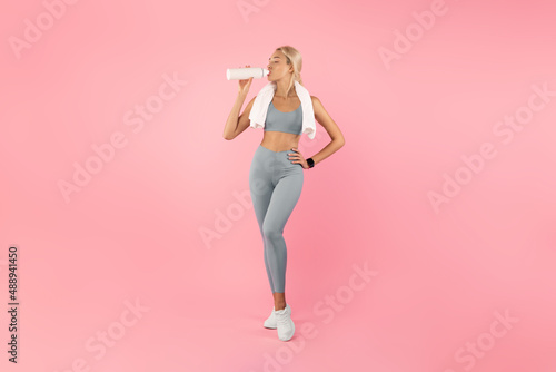 Sporty woman drinking water from bottle after exercising