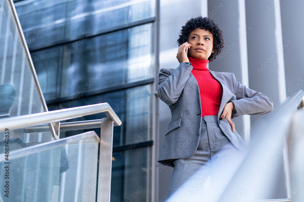 Elegante mujer afroamericana utilizando el teléfono móvil en un edificio de oficinas Elegante mujer afroamericana utilizando el teléfono móvil en un edificio de oficinas