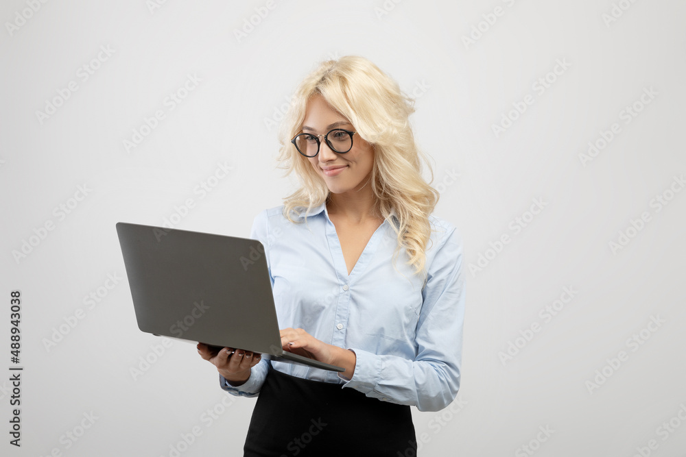 Successful businesswoman in formal wear using laptop computer over light grey studio background, copy space Successful businesswoman in formal wear using laptop computer over light grey studio background, copy space