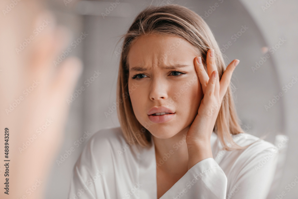Mirror reflection of upset lady looking at mirror and touching her forehead, having dry skin problem, first wrinkles - obrazy, fototapety, plakaty 