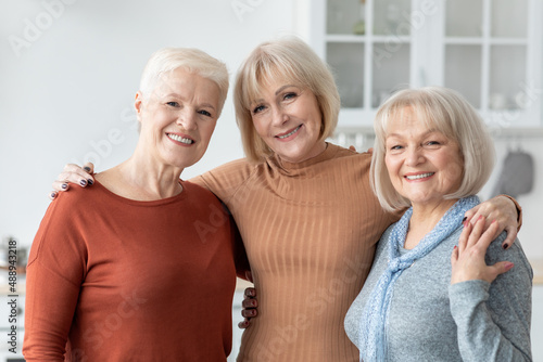 Portrait of happy elderly ladies posing at kitchen