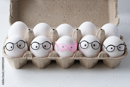 Packing white eggs in a cardboard box. Four eggs in glasses, one egg in rose-colored glasses.