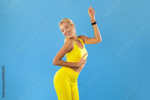 Smiling Young Woman In Sportswear Listening To Music And Dancing © Prostock-studio