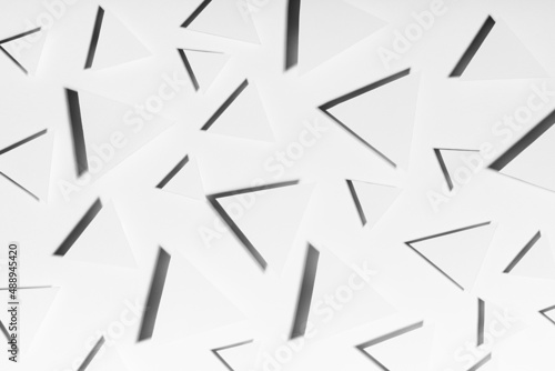 White triangles geometric pattern in hard light with strict black shadows in random  top view. Minimalist modern abstract background.