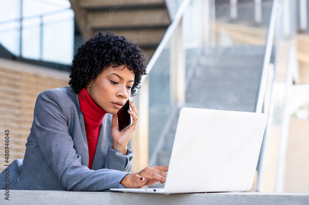 An elegant African American woman working on her laptop in an office building An elegant African American woman working on her laptop in an office building